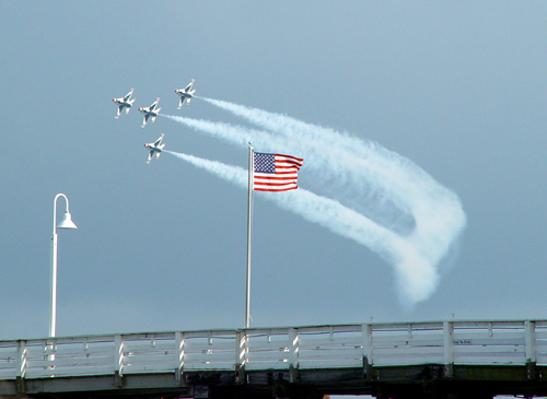 Free Picture: Photo of four F-16 Fighting Falcons flying in formation just behind an American flag at an airshow.