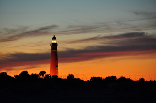 Free Picture: Photo of the Ponce Inlet lighthouse glowing in front of a sherbet orange color sky in Ponce Inlet, FL.