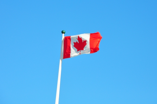 Free Picture: Photo of the red and white Canadian flag flying in the wind showing off the maple leaf.