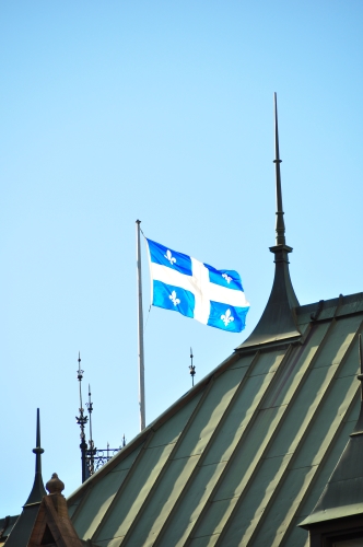 Free Picture: Photo of the province of Quebec flag flying above a hotel adorning the fleur de lis.